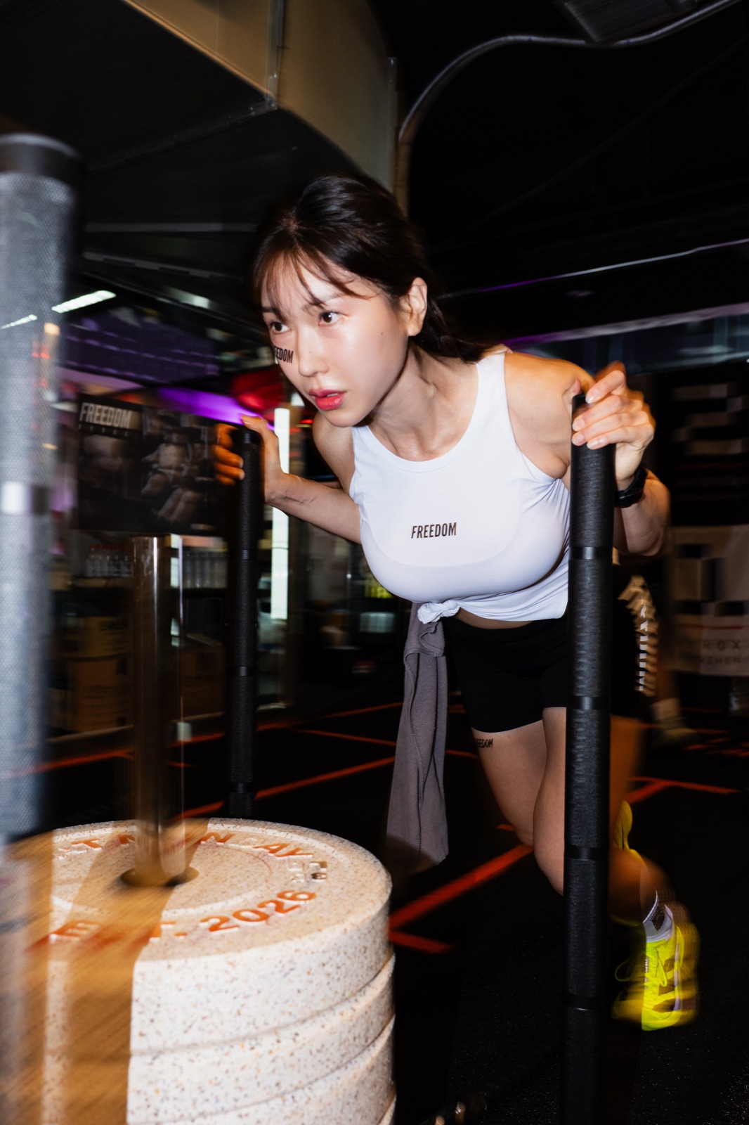 Athlete in FREEDOM kit pushing a sled loaded with SWEAT MONDAY 2026 engraved plates