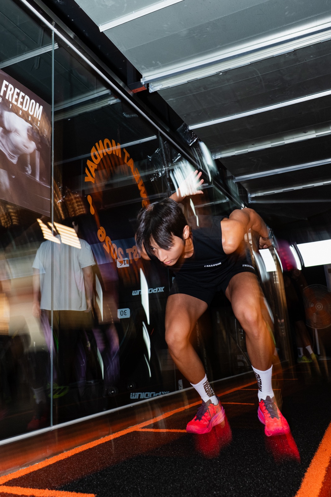 Motion-blur sprint start in front of the SWEAT MONDAY window graphic at the FREEDOM community workout